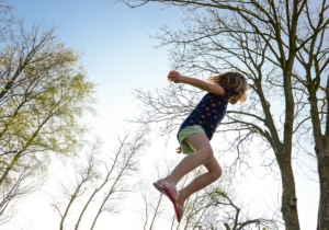 healthy energetic child jumping in woods on spring day