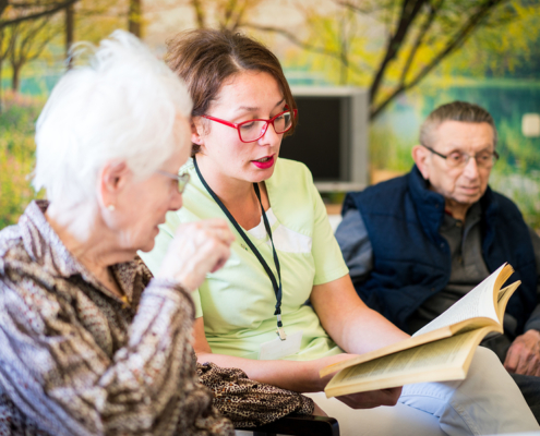 Nurse reading book to elderly group of people
