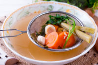 veggie soup broth in large bowl with scoop